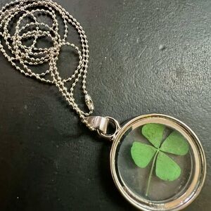 Delicate metal & glass pendant featuring a real preserved green four-leaf clover